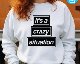 May include: White sweatshirt with the text "it's a crazy situation" in a black and white design. The text is stacked in three lines, each within a black rectangle. The sweatshirt has long sleeves and a crew neck.