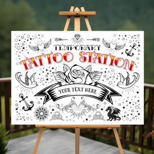 以下が含まれることがあります： 「Temporary Tattoo Station」と黒と赤の文字が書かれた白い看板。看板には、バラ、羽根つきのハート、錨、鳥、ドラゴン、星など、さまざまなタトゥー風の画像が描かれています。