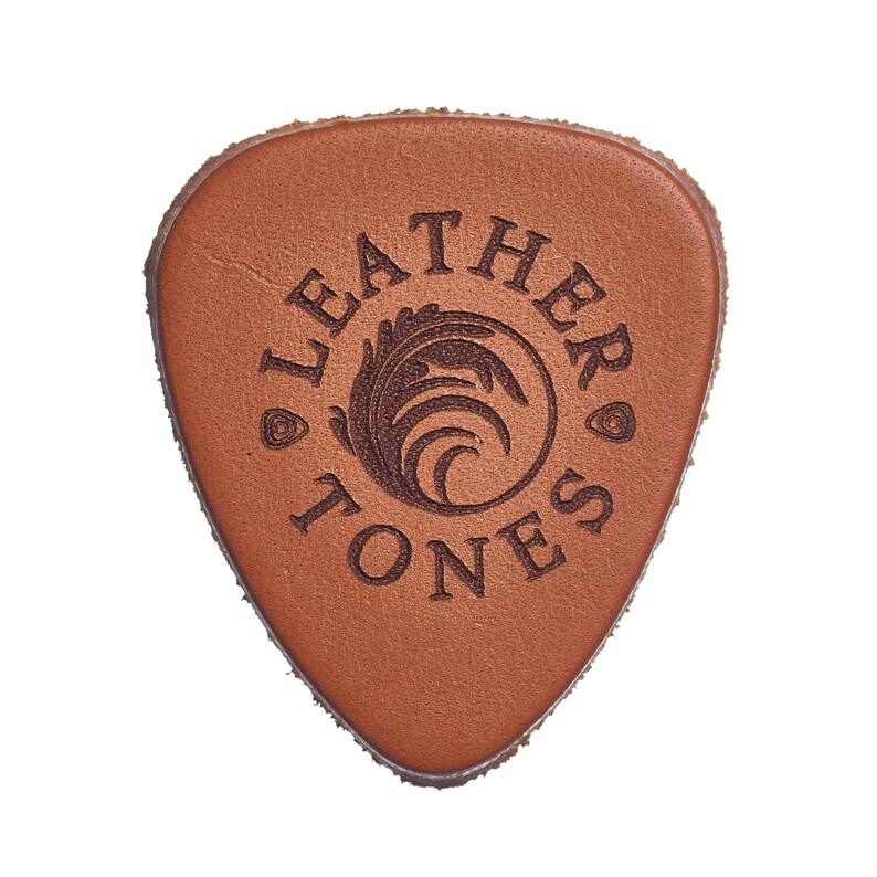 May include: A brown leather guitar pick with the words "Leather Tones" and a stylized leaf design.