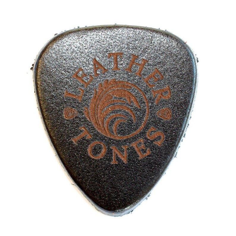 May include: A black leather guitar pick with the words "Leather Tones" and a logo of a stylized wave in a circle, all in brown.