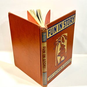 Może przedstawiać: Wydanie w twardej oprawie zatytułowane Fun in Story, Easy Growth in Reading. Okładka jest pomarańczowa z niebieskim banerem i ilustracją słonia pod palmą. Grzbiet jest beżowy z niebieskim tekstem i tytułem Fun in Story na okładce.