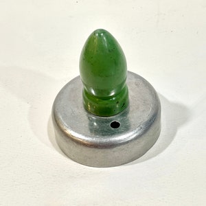May include: A vintage cookie cutter with a green, bullet-shaped handle and a circular, silver-colored metal base. The cutter has a small hole on the side. The design is simple and classic, suitable for baking.