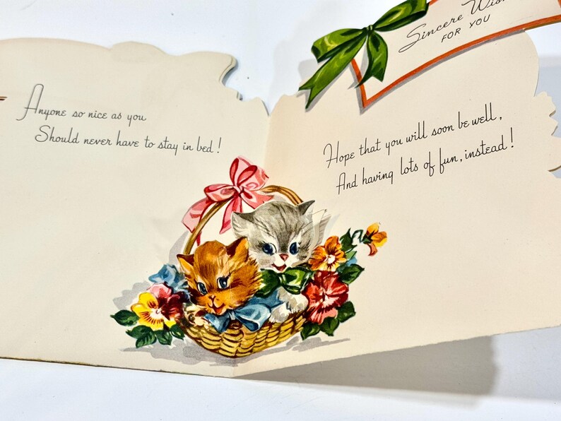 May include: Vintage get-well card featuring two kittens in a woven basket with flowers. The kittens are orange and gray, with blue bows. The card has handwritten text that reads "Anyone so nice as you should never have to stay in bed!" and "Hope that you will soon be well."