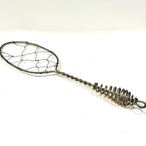 May include: A vintage metal skimmer with a wire mesh oval head and a twisted handle that transitions into a coiled spring grip. The skimmer is made of silver-toned metal and is set against a white background.