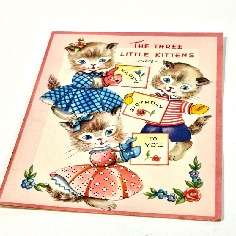 May include: Vintage birthday card featuring three kittens dressed in colorful outfits. The kittens hold signs that read "Happy Birthday To You." The card has a pink border and floral accents.