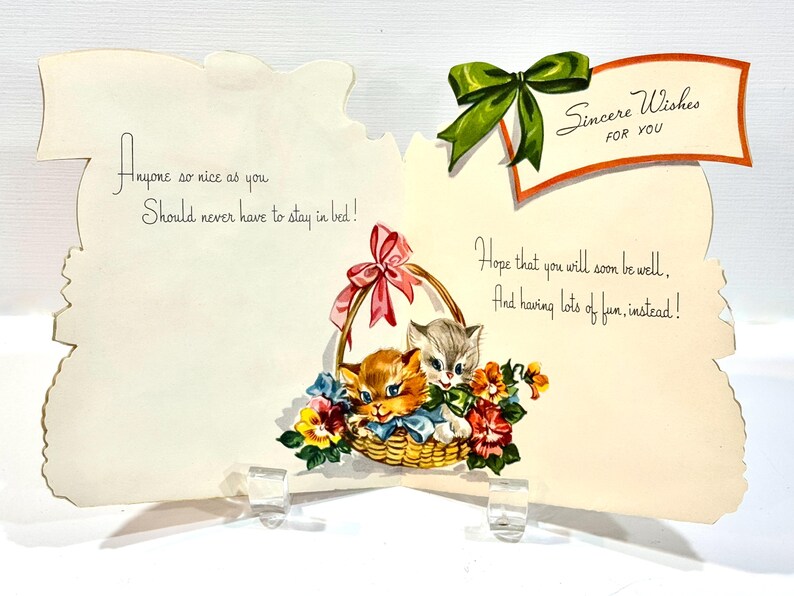 May include: Vintage greeting card with a basket of kittens and flowers. The card has a green bow and a banner that reads "Sincere Wishes for You." Text on the card includes "Anyone so nice as you should never have to stay in bed!" and "Hope that you will soon be well."