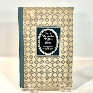 Könnte beinhalten: Vintage Kochbuch mit dem Titel "Electric Refrigerator Recipes and Menus". Das Cover zeigt ein Rauten- und Schneeflockenmuster in Creme und Grau. Ein dunkel türkisfarbenes Rechteck enthält den Titel in eleganter Schrift. Der Buchrücken ist türkis.