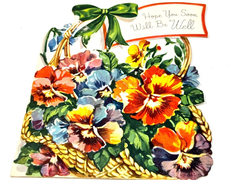 May include: A vintage get-well card featuring a basket overflowing with colorful pansies in shades of orange, yellow, blue, and purple. A green bow adorns the top, and a banner reads "Hope You Soon Will Be Well."