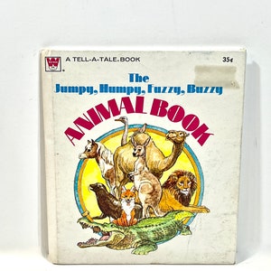 May include: Vintage children's book titled "The Jumpy, Humpy, Fuzzy, Buzzy Animal Book." The cover features illustrations of various animals, including a camel, lion, kangaroo, and crocodile, set against a yellow and blue circular background.