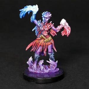 May include: A painted miniature figurine of a female figure with purple skin, red and orange clothing, and blue and white translucent wings. The figure is standing on a purple and black base.