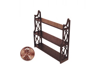 May include: A miniature three-tiered wooden shelf with decorative cutouts and a dark brown finish. The shelf is shown next to a penny for scale. The shelf is approximately 4 inches tall.
