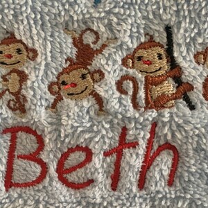 May include: A blue towel with embroidered monkeys and the name "Beth" in red.