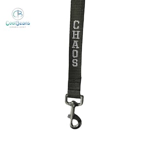 May include: A green dog lead with a silver clip and the word "CHAOS" embroidered in white.