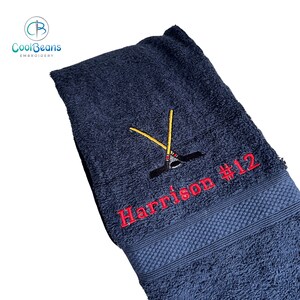 May include: A dark blue towel with red embroidery of a hockey stick and the text "Harrison #12".