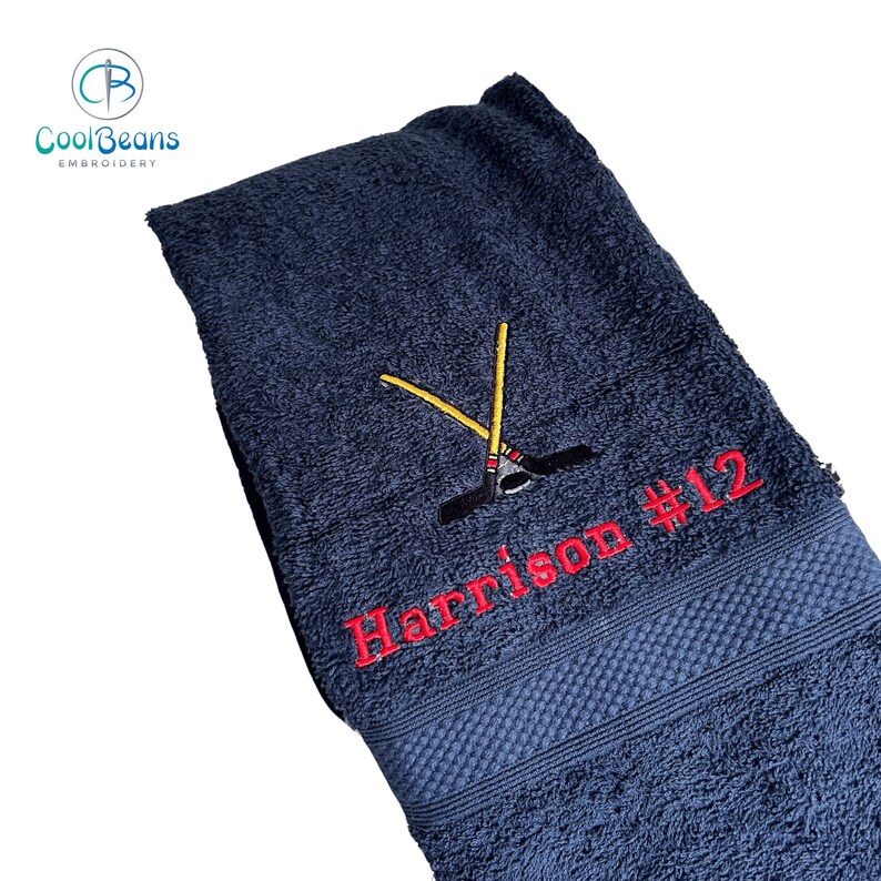 May include: A dark blue towel with red embroidery of a hockey stick and the text "Harrison #12".