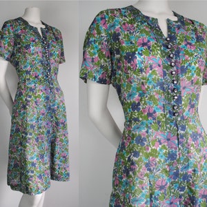 May include: A vintage floral print dress with a short sleeve, a v-neck, and a button-up front. The dress is made of a lightweight fabric and has a fitted bodice and a flared skirt.