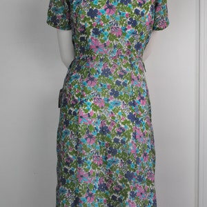 May include: A vintage floral print dress with a short sleeve, a V-neck, and a fitted silhouette. The dress is made of a lightweight fabric and features a colorful floral pattern in shades of pink, blue, green, and white.