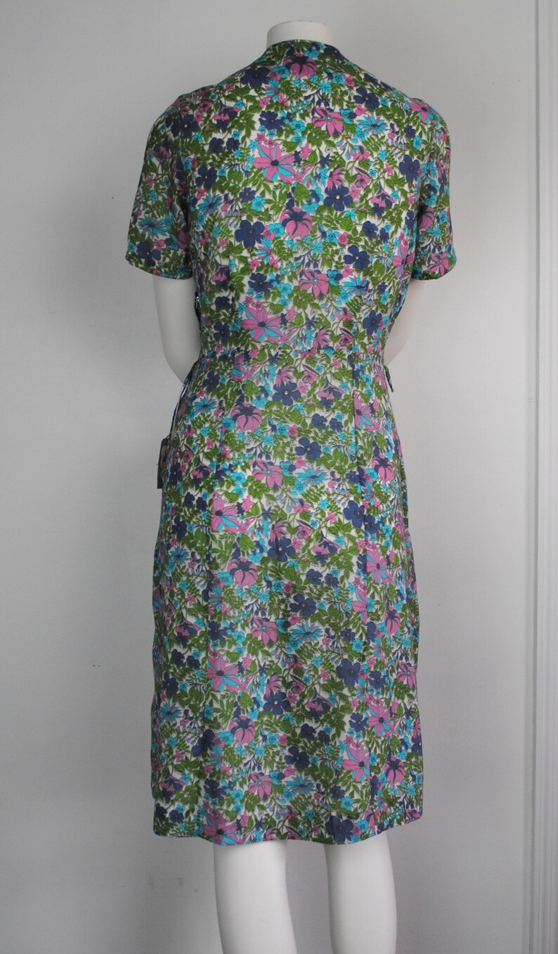 May include: A vintage floral print dress with a short sleeve, a V-neck, and a fitted silhouette. The dress is made of a lightweight fabric and features a colorful floral pattern in shades of pink, blue, green, and white.