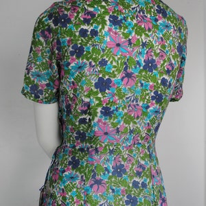 May include: A white dress with a short sleeve and a floral print in shades of blue, pink, and green.