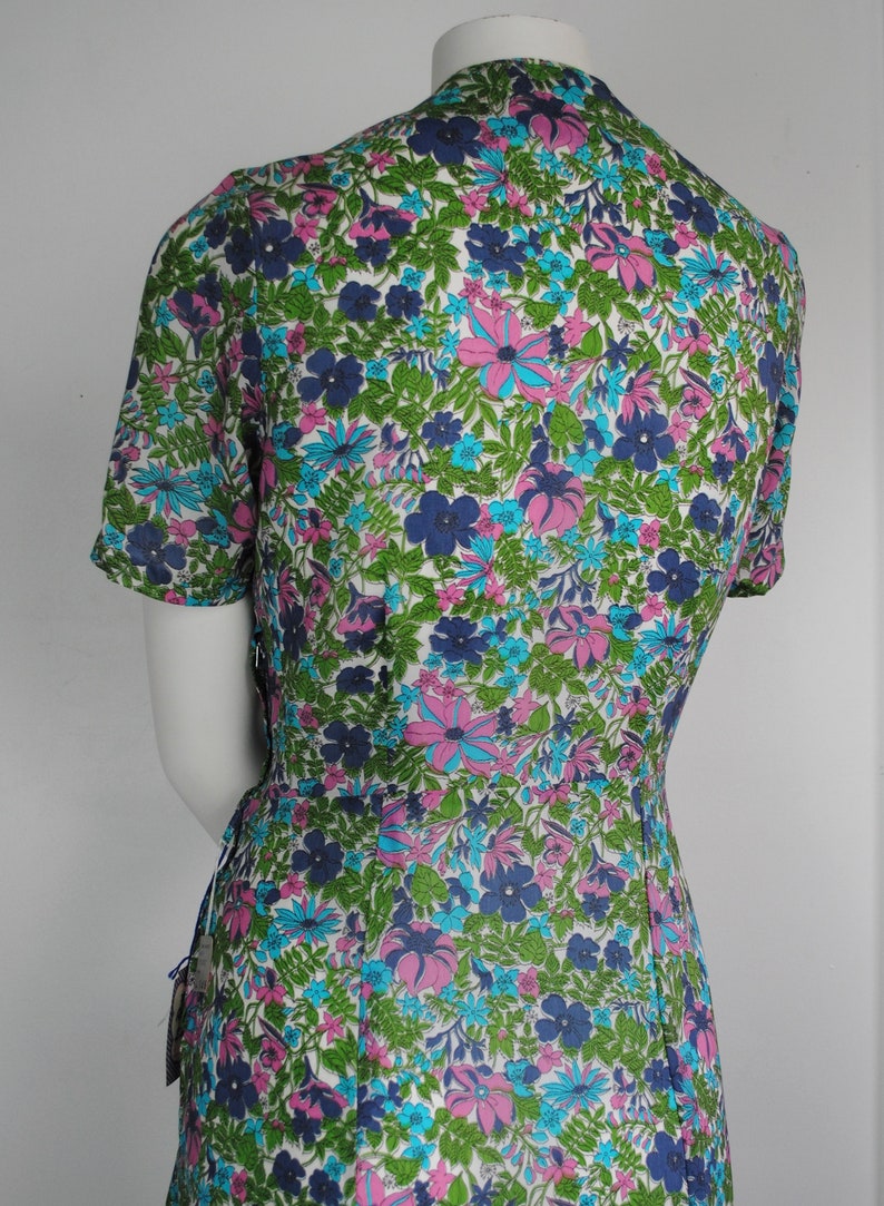 May include: A white dress with a short sleeve and a floral print in shades of blue, pink, and green.