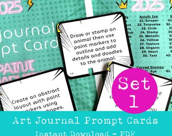 May include: A set of colorful art journal prompt cards with a pink circle that says "Set 1" in white text. The cards have black borders and white text on a green background. The text on the cards includes prompts like "Create an abstract layout with paint" and "Draw or stamp an animal then use paint markers to outline and add details and doodles to the animal."
