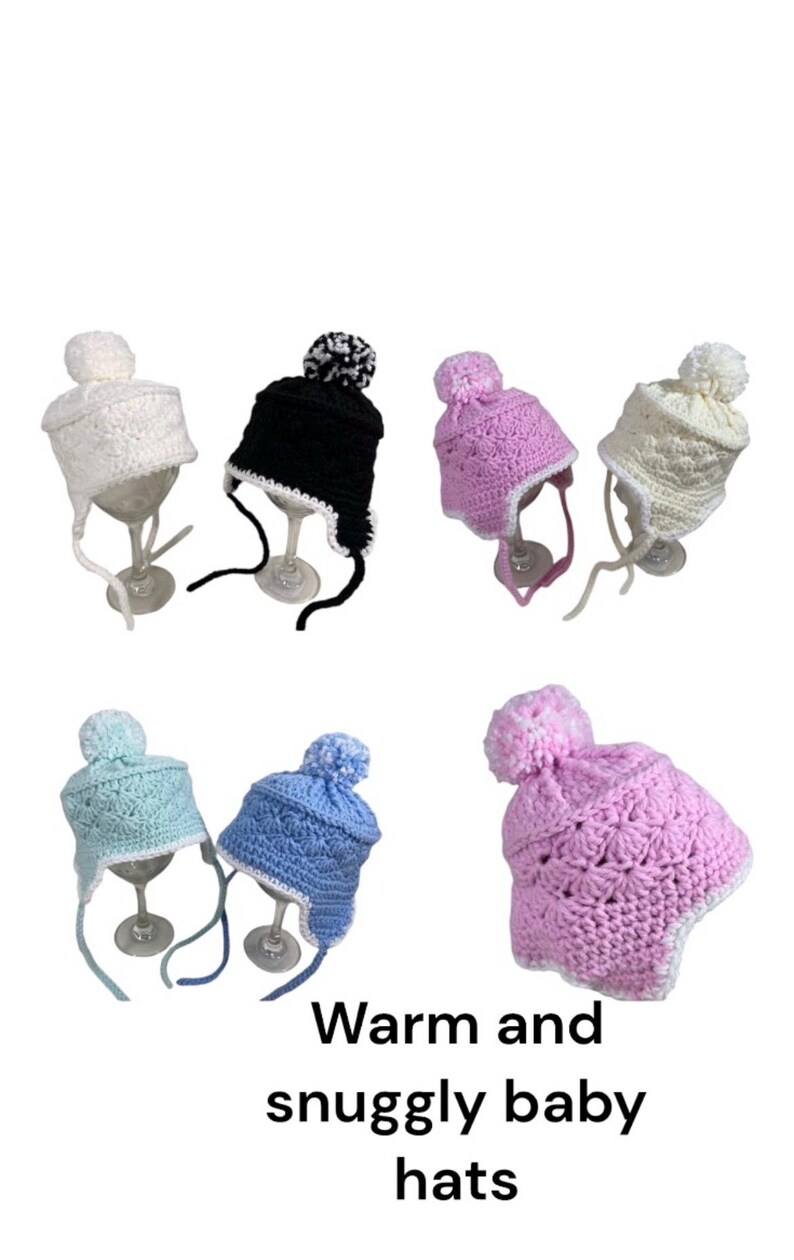 May include: Six crocheted baby hats with pom-poms. The hats are in various colors, including white, black, pink, light blue, and a darker blue. The hats have ear flaps and are tied with a string under the chin.