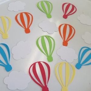 May include: Assortment of paper cutouts of hot air balloons in various colors, including red, orange, yellow, green, blue, and pink. There are also white paper cutouts of clouds.