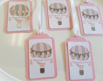 May include: Five pink and white thank you gift tags with a hot air balloon design. The balloons are gray and pink with silver glitter accents and a silver glitter banner. The tags say "Thank you" in a white font.