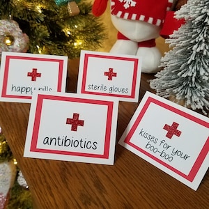 May include: Four red and white gift tags with a red cross and a festive message. The tags read "happy pills", "sterile gloves", "antibiotics", and "kisses for your boo-boo".