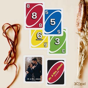 May include: A collection of Uno playing cards, some with numbers and colors, and two custom cards. One custom card features a couple's photo and the text "Mr. & Mrs. Adams 10.04.2025". The other card has the text "Mr. & Mrs. Adams 10.04.2025" on a red background.