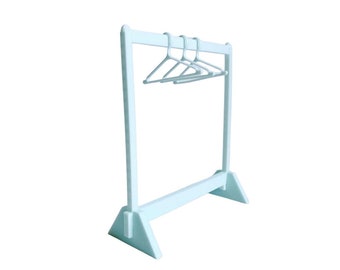 May include: A white freestanding clothing rack with three white plastic hangers. The rack has a triangular base.