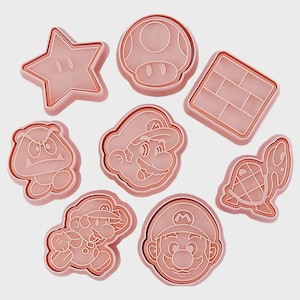 Peut inclure: Ensemble de huit emporte-pièces en plastique rose, de formes variées : étoile, champignon, brique, Goomba, visage de Mario, Mario en mouvement et tortue. Parfaits pour les biscuits.