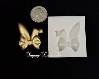 May include: A silicone mold for making a bow with bunny ears. The mold is white and shows a detailed impression of the bow and ears.