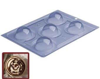 May include: A clear plastic mold with six round cavities for making chocolate domes. The mold is on a white background.