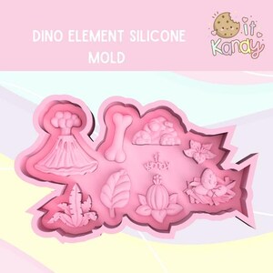 Op de afbeelding: Roze siliconen mal met 9 verschillende dinosaurussen-thema vormen, waaronder een vulkaan, bot, wolk, bloem, blad en een dinosaurus ei. De mal is gelabeld "Dino Element Silicone Mold".