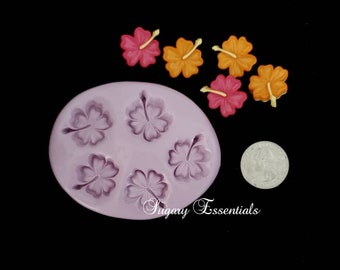 May include: Purple silicone mold with six hibiscus flower shapes.  The mold is on a black surface with five small, colorful hibiscus flower decorations.