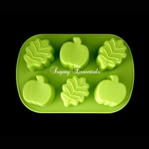 May include: Green silicone mold with six cavities shaped like pumpkins and leaves. The mold is designed for making candy, chocolate, or soap.