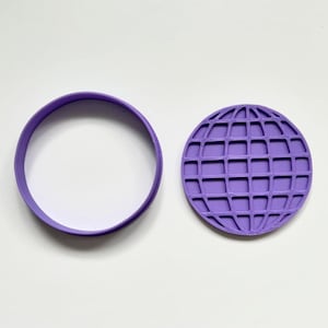 Peut inclure: Un ensemble de découpoirs à biscuits violets. Il comprend un anneau rond et un découpoir en forme de globe avec un motif quadrillé. L'ensemble est en plastique. Les articles sont sur une surface blanche.