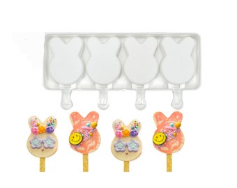 May include: A clear plastic mould with four bunny-shaped popsicle moulds. The mould is filled with white popsicles. Four decorated bunny-shaped popsicles are shown below the mould.