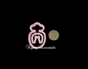 May include: Pink plastic cookie cutter shaped like a snowman with a hat and a carrot nose. The cookie cutter is about the size of a US quarter.