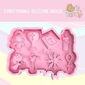 Könnte beinhalten: Rosa Silikonform mit verschiedenen religiösen Symbolen wie einem Engel, einem Kreuz, einem Kelch, einer Bibel, einer Kerze, einem Rosenkranz und einem Stern. Die Form ist zum Herstellen von essbaren Dekorationen für eine Taufe gedacht.