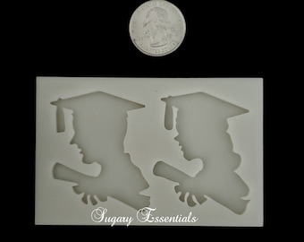 May include: White silicone mold with two graduation cap silhouettes holding diplomas. The mold is approximately the size of a US quarter. The text "Sugary Essentials" is printed on the bottom of the mold.