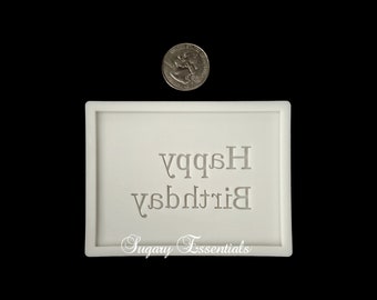May include: White silicone mold for baking or crafting. The mold is rectangular and features the text "Happy Birthday" in a decorative font. The mold is made by Sugary Essentials.