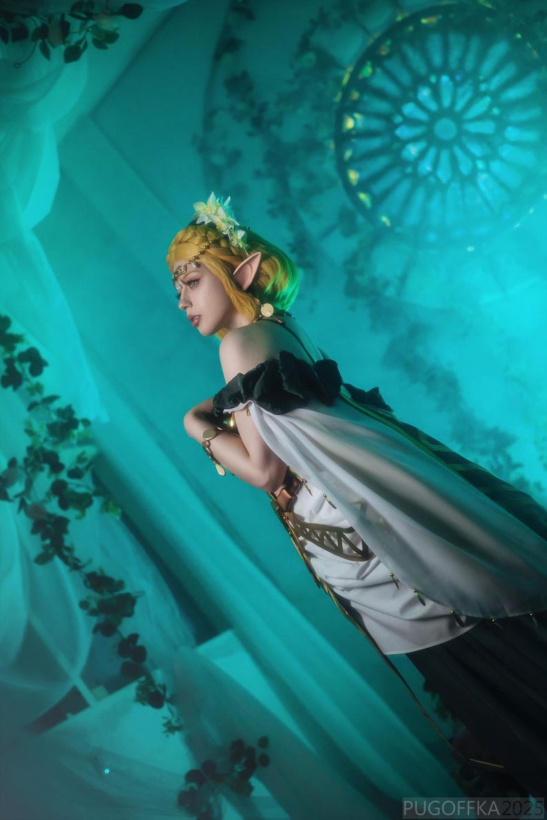 May include: A person in a fantasy-themed costume with a yellow wig, pointed ears, and a white and black dress. The background is a teal color with a stained-glass window design. The image has the text "PUGOFFKA 2023" in the bottom right corner.