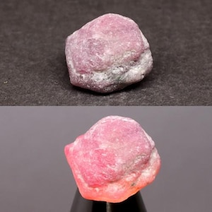 May include: A raw, unpolished gemstone with a rough, irregular surface texture. The stone displays a vibrant pink and magenta color palette, featuring opaque sections mixed with translucent areas that glow when illuminated from below.