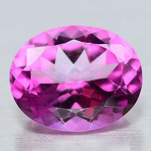 May include: A faceted, oval-shaped pink gemstone. The gem has a brilliant cut with numerous facets that reflect light, creating a sparkling effect. The colour is a vibrant, medium pink, with a hint of purple.