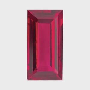 Puede incluir: Una piedra preciosa rectangular facetada de un color rojo intenso y vibrante. La piedra presenta un corte escalonado con líneas geométricas claras y superficies pulidas que reflejan la luz, creando una apariencia translúcida con tonos rojos.