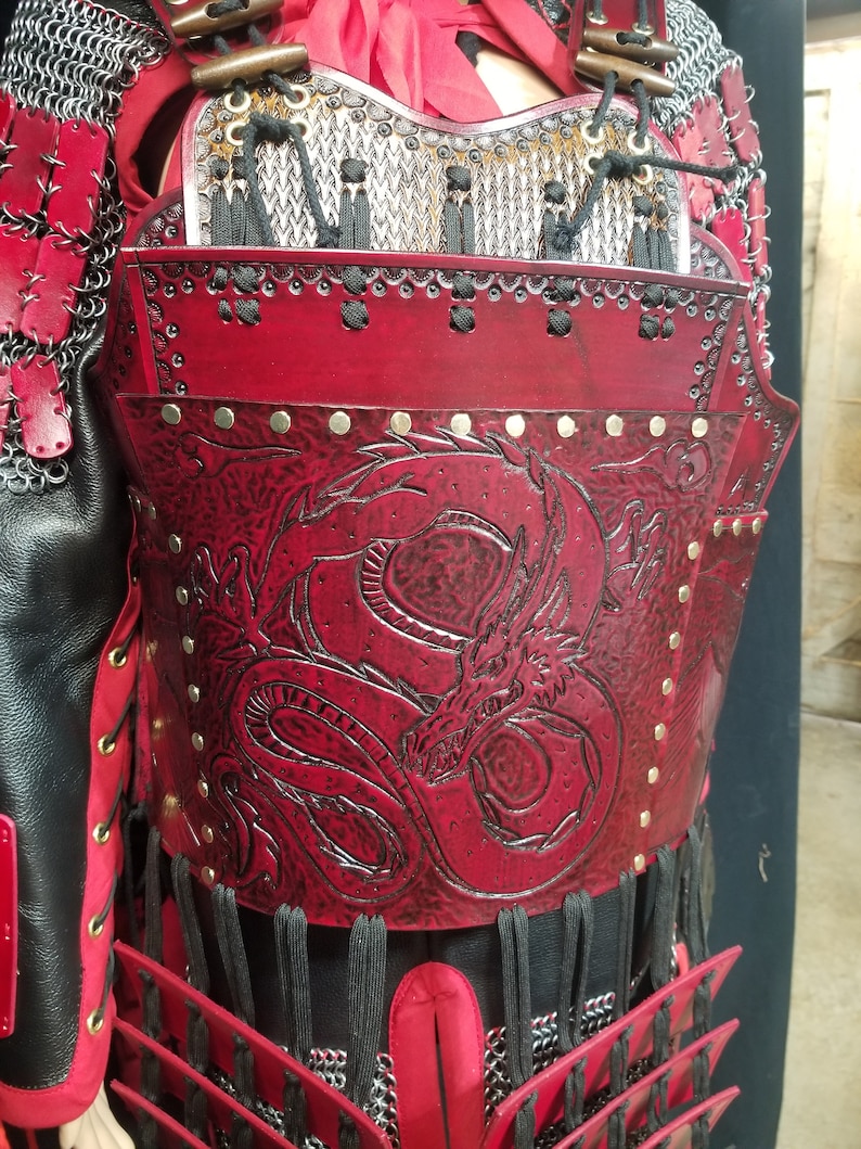May include: Red leather armor with a dragon design and metal accents. The armor is worn over a chainmail shirt.