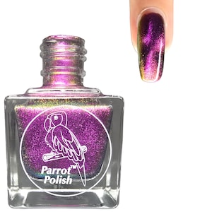 May include: A square glass bottle of Parrot Polish nail polish with a purple iridescent shimmer. The bottle has a white label with a parrot illustration and the brand name. A painted nail displays the same color.