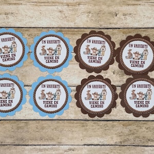 May include: Eight circular paper cutouts with scalloped edges, four in light blue and four in dark brown. Each features a central illustration of a cowboy hat, boots, and a barrel, with the text UN VAQUERITO VIENE EN CAMINO printed in black.